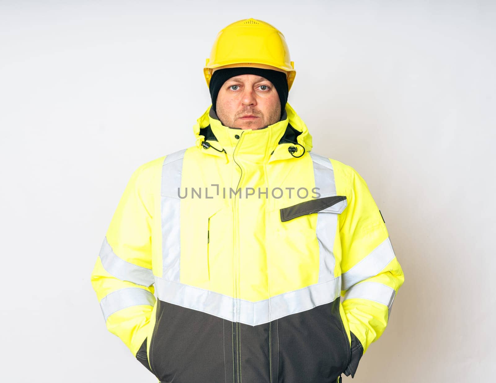 a man wearing a yellow working winter jacket and a yellow safety helmet . High quality photo