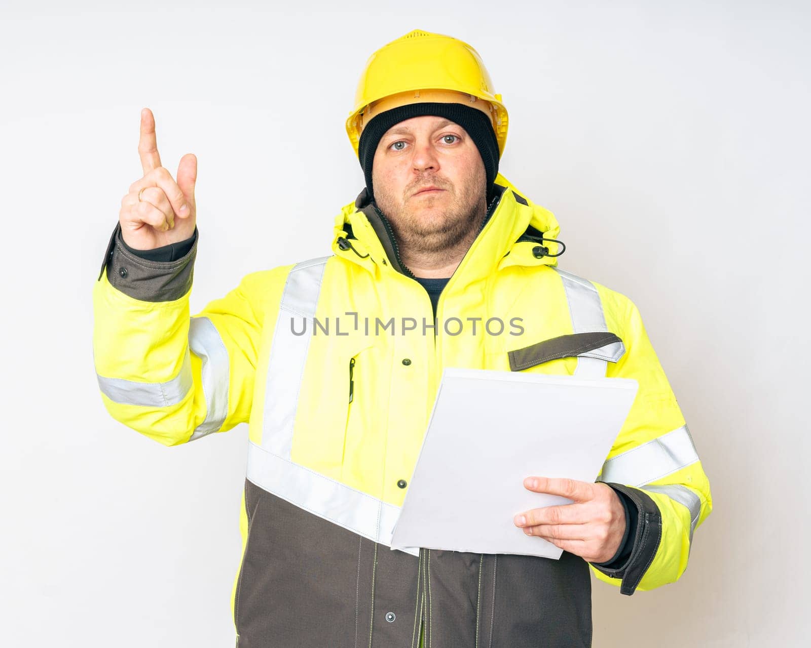 a man in a yellow working winter jacket, yellow safety helmet with papers in his hands. High quality photo