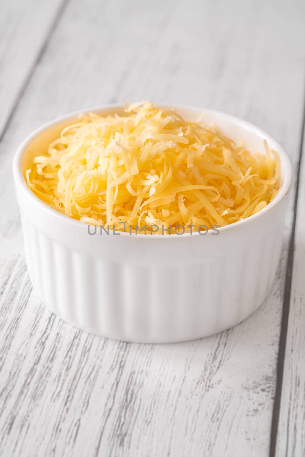 Bright shredded cheddar cheese in white bowl, perfect for topping or melting