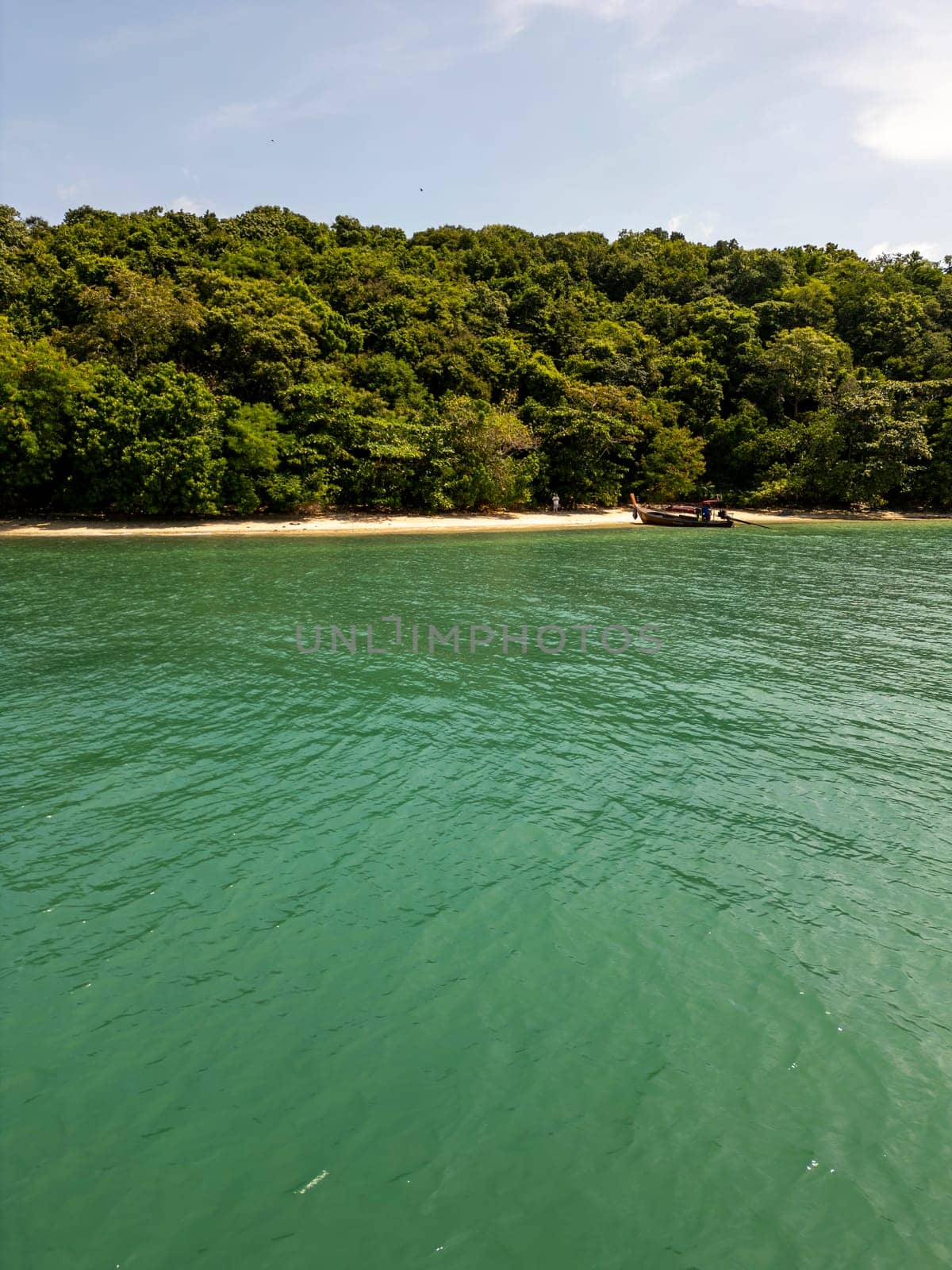 Drone shot of tropical sailboats in a turquoise bay near the harbor, boats floating in crystal clear water near a scenic Thai island with rocky beach. Picturesque shoreline with fun activities.