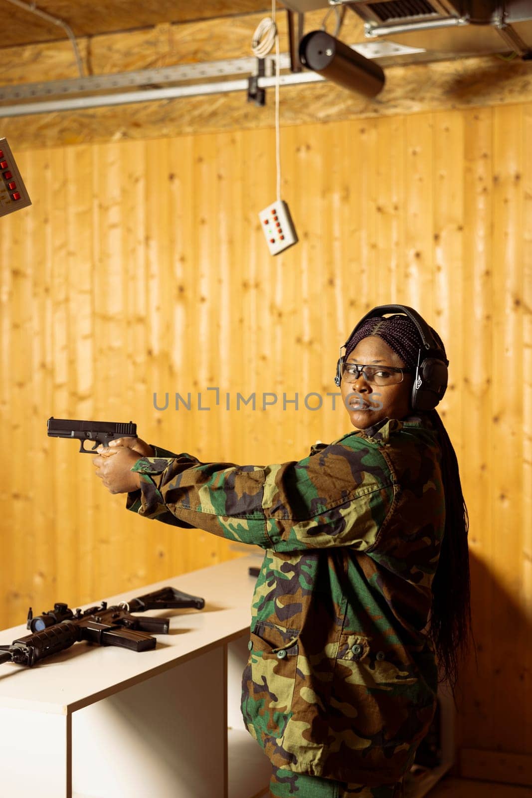 Portrait of woman at shooting range holding pistol, participating in elite level marksmanship training program. Person at firing range doing intensive shooting course with handguns