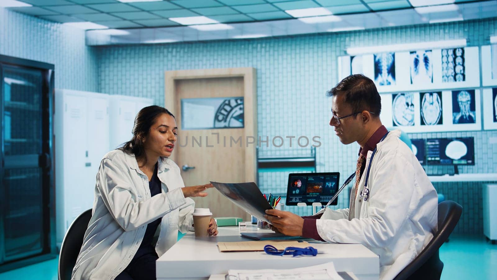 Specialist and patient discussing diagnostic results in a modern medical office, establishing advanced technology to present x ray imaging results and MRI scans. Health care management. Camera B.