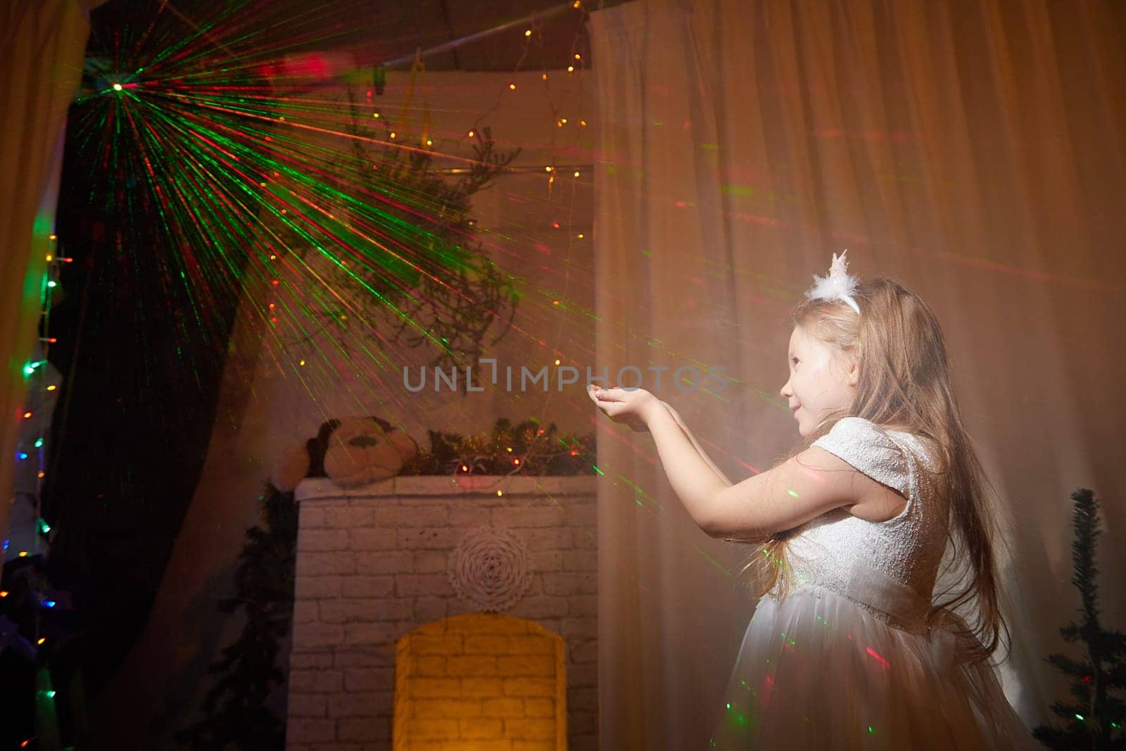 A child happily interacts with colorful lights in a beautifully decorated room for Christmas and New Year celebrations.