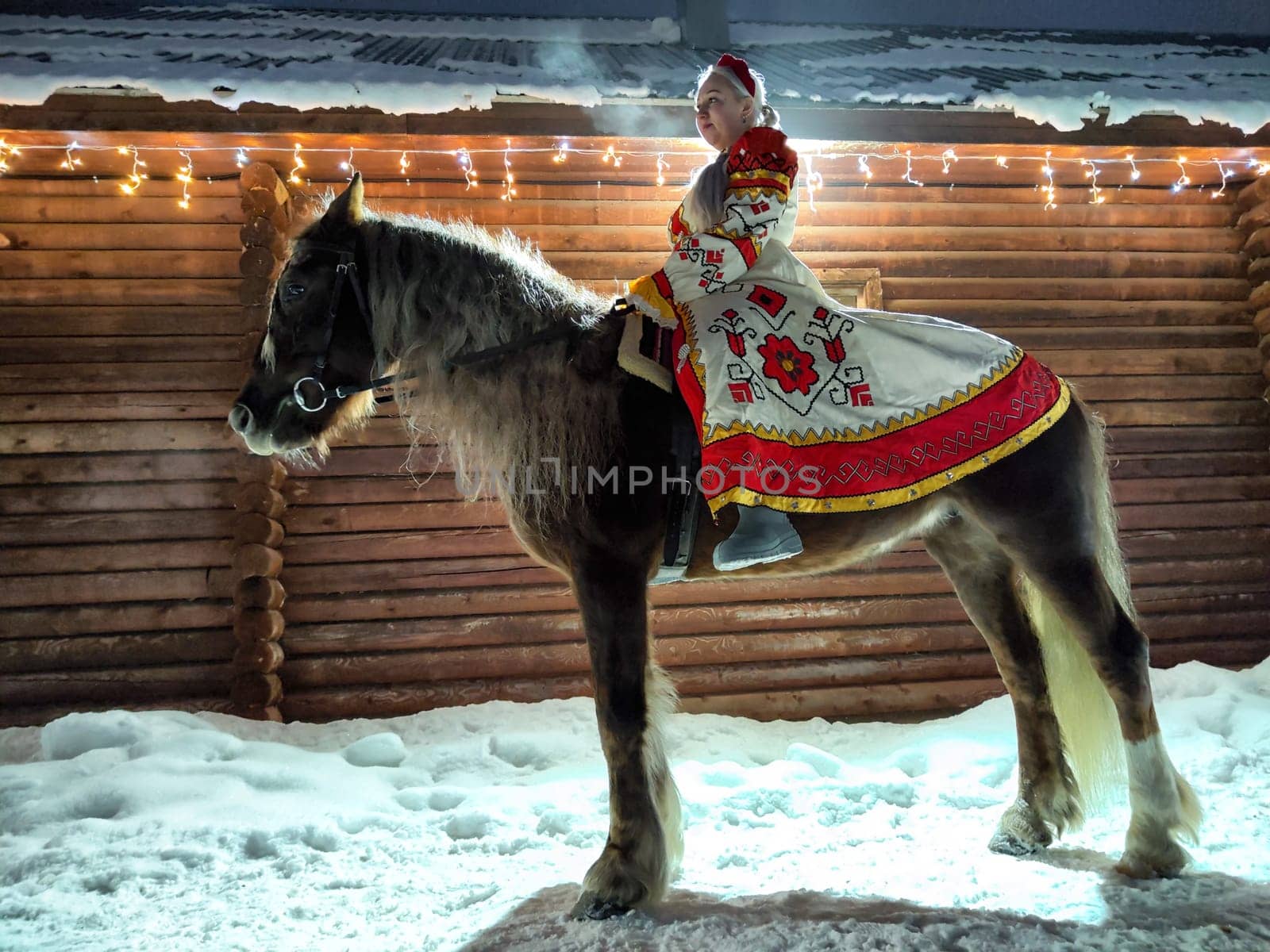 A Russian girl in traditional attire enjoys a photoshoot with a horse amidst winter decorations for Maslenitsa.