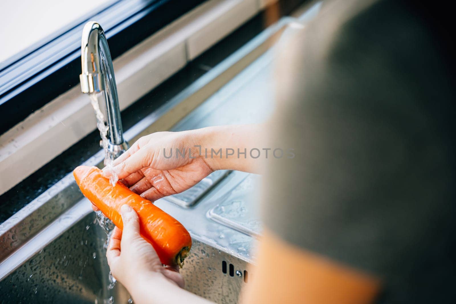 Hygienic vegetable prep, A young woman washes carrots in the kitchen sink highlighting clean eating and organic food. Emphasizing washing fresh vegetables before cooking.