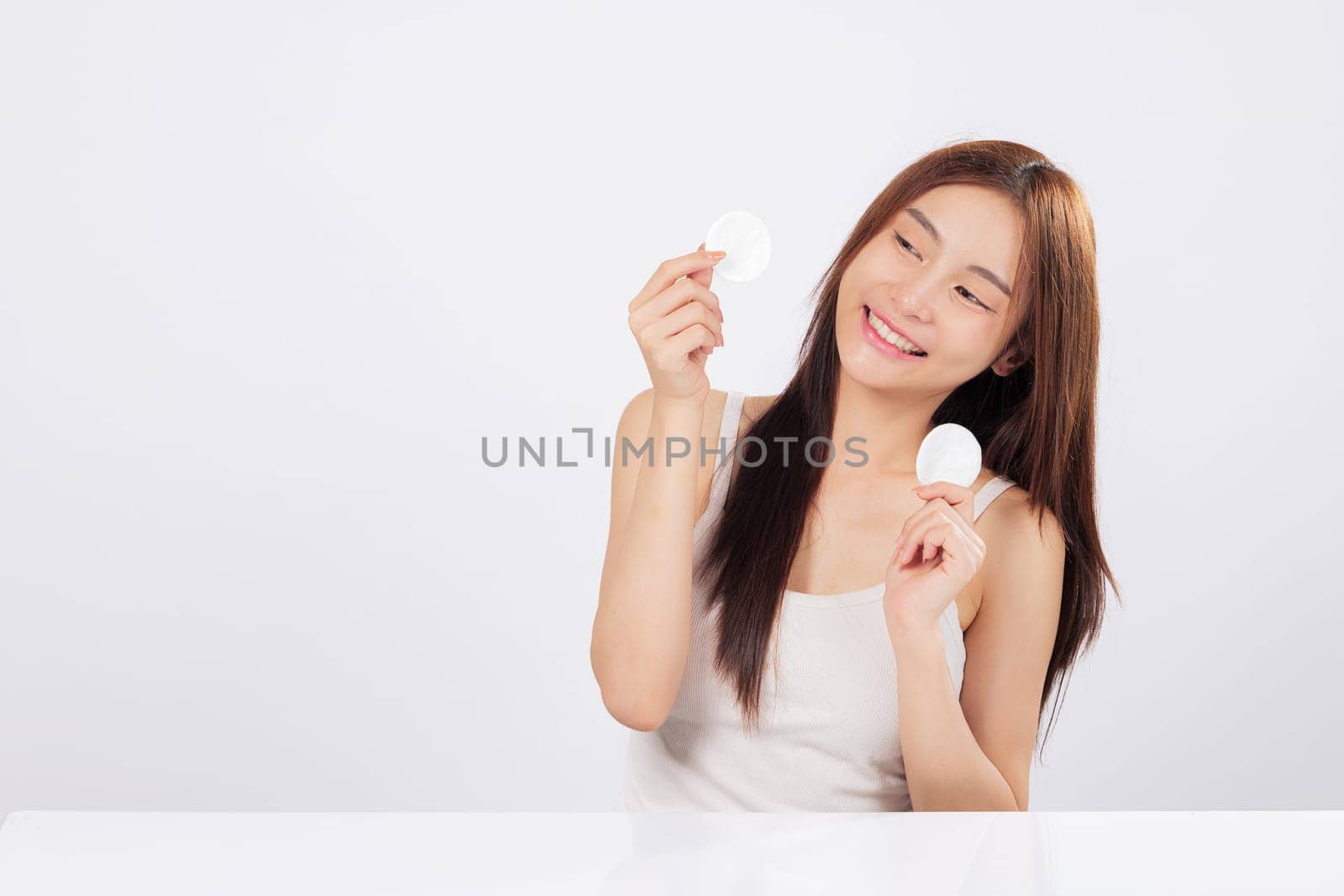 Cotton pad slides on her skin as another cotton pad rests in her hand, helping her reveal a natural and clean beauty with confidence in every step of her facial care. isolated studio white background