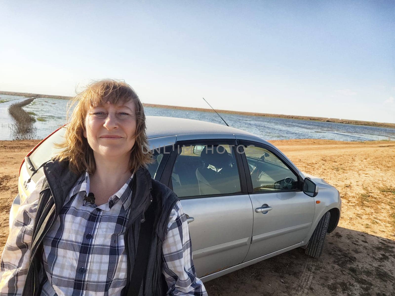 Adult woman enjoys a selfie moment by the lakeside while exploring a beautiful travel destination on her adventure.