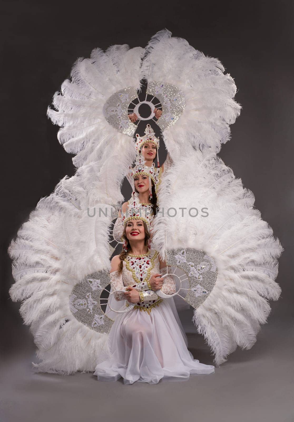 Full body side view of elegant bride in white dress and veil with bouquet of white flowers on black background
