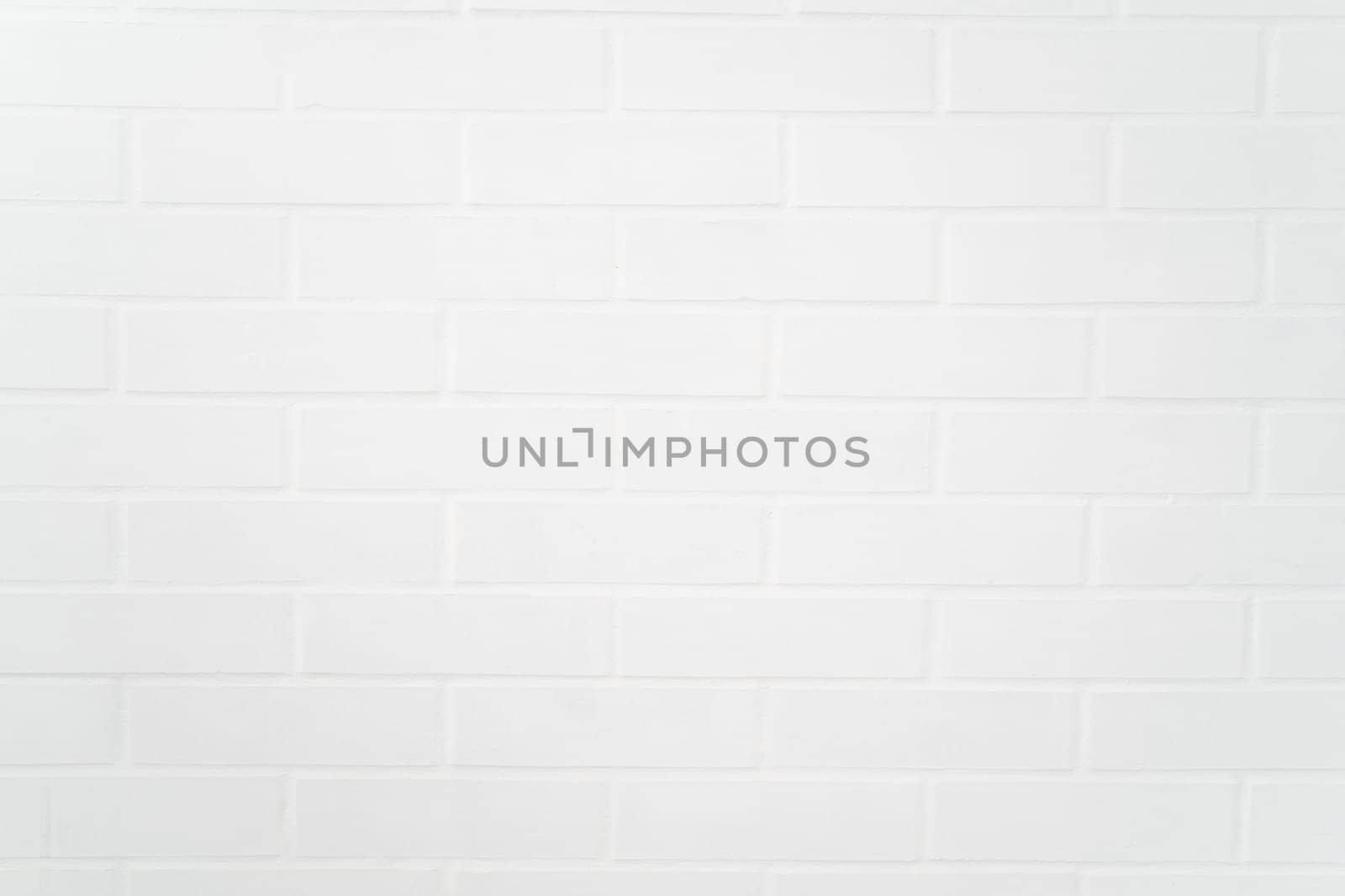Flat closeup of white painted brick wall texture, showcasing uniform pattern, grout lines, and matte finish ideal for backgrounds or architectural design use.