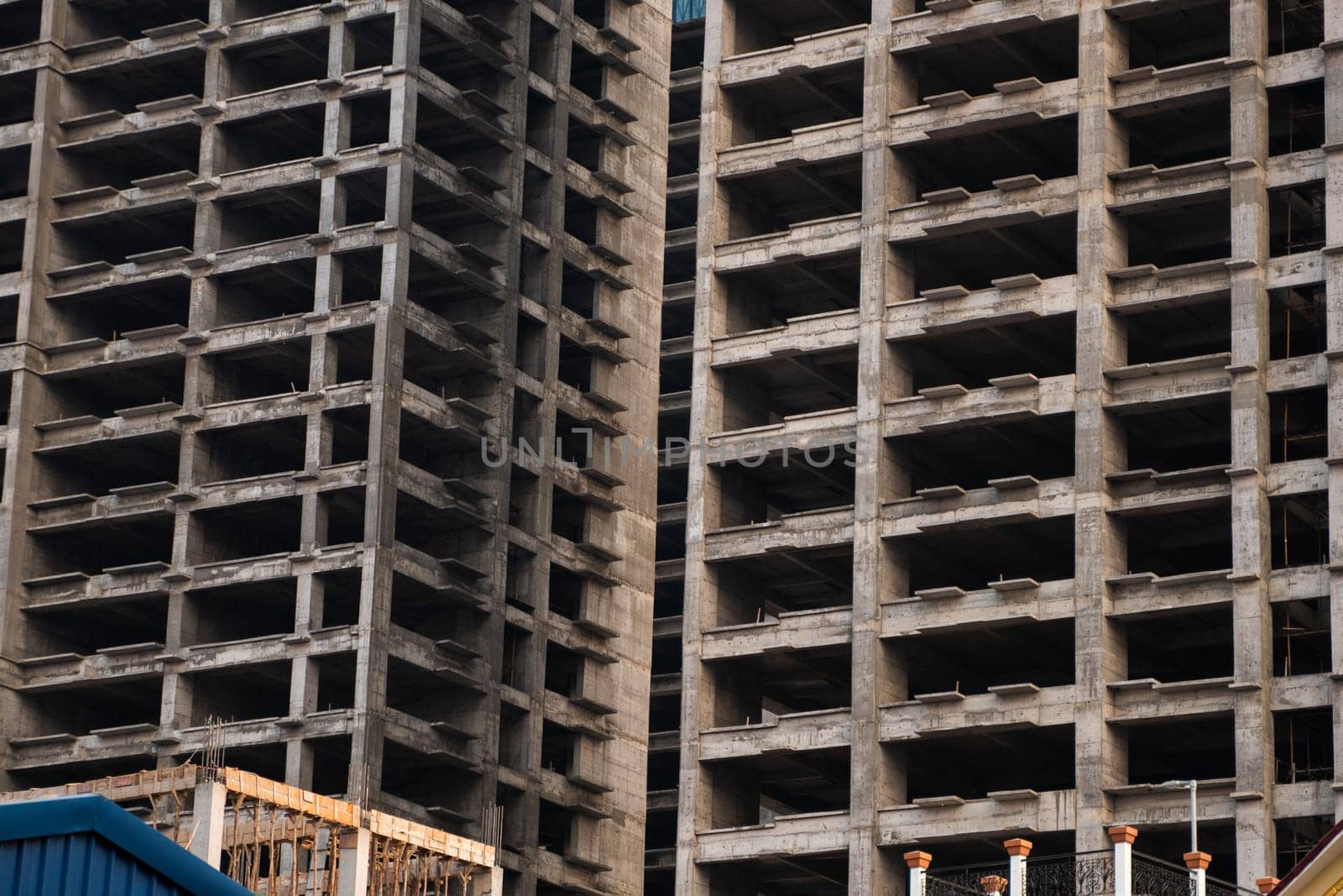 Densely framed shot of two unfinished concrete towers, focusing on depth, repetition, and shadow play between structural elements of modern construction.