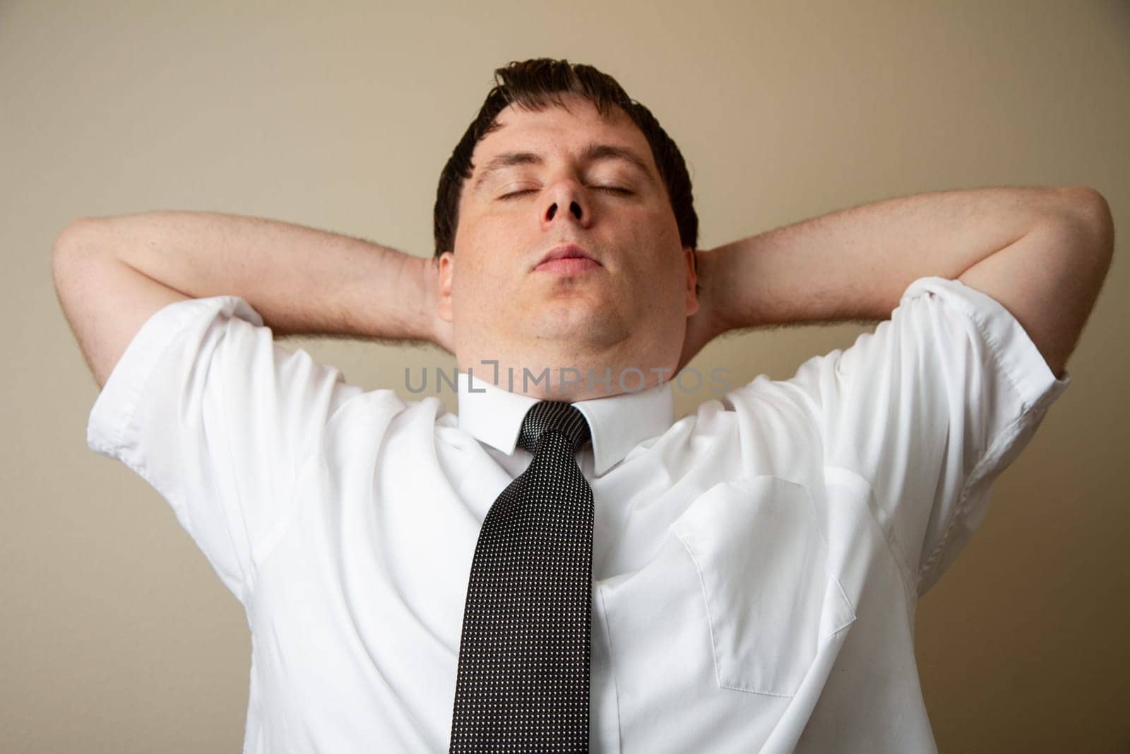 A man in a white shirt and black tie is relaxing with his arms behind his back. Concept of calm and relaxation, as the man is taking a break from his busy day