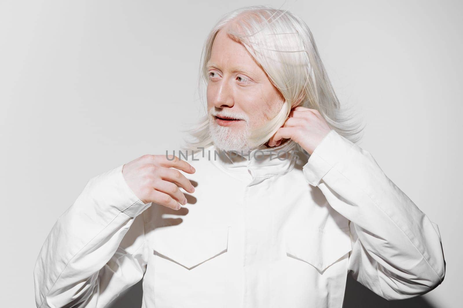 This image features an elderly man with striking long white hair and a beard, dressed in a clean white jacket, set against a simple white background The composition evokes themes of wisdom, calmness, and a serene aesthetic, making it ideal for various creative projects exploring age, beauty, or minimalism