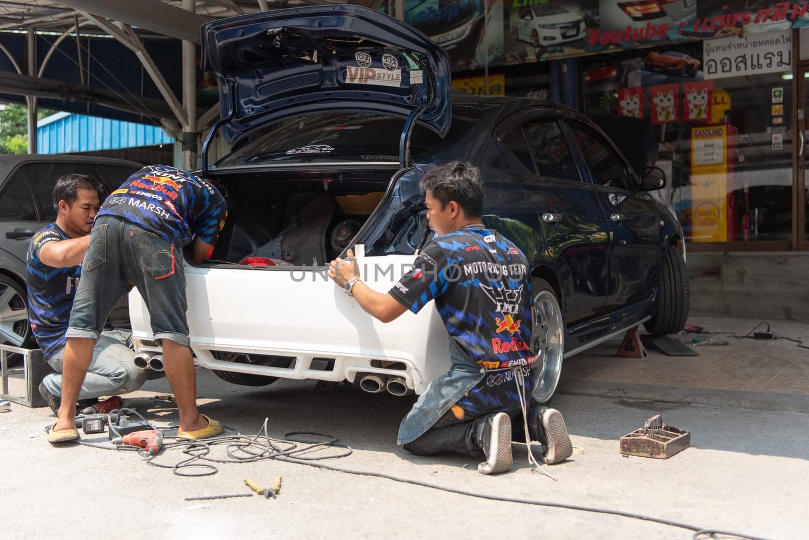 Bangkok, Thailand - April 4, 2024 : Unidentified denter or car mechanic serviceman check and fix body work and fiber bumper body part for fix and repair problem at car garage or repair shop