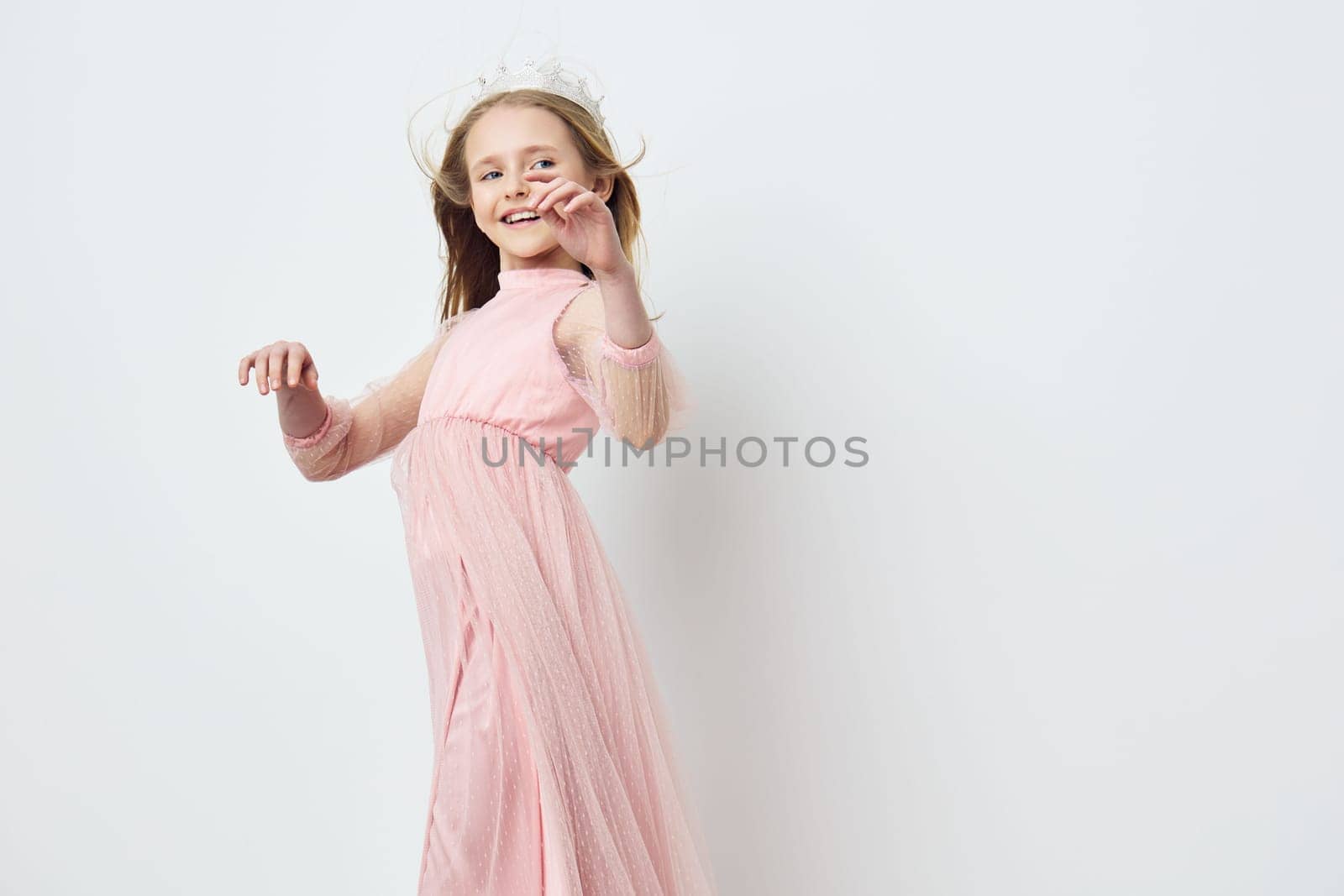 A joyful young girl wearing a flowing pink dress dances gracefully in front of a clean background, embodying innocence and happiness, perfect for seasonal celebrations