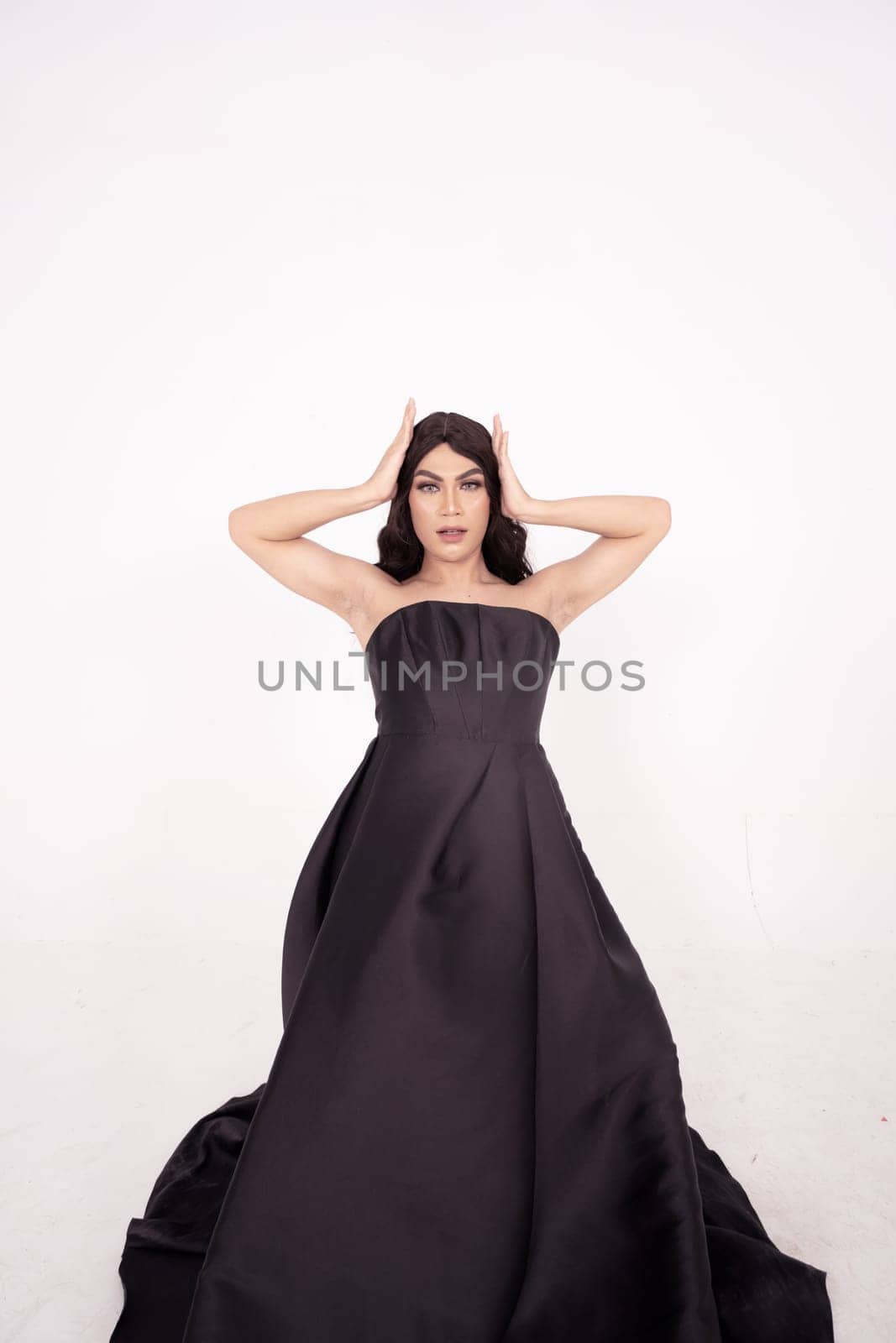 A whole body of an Asian woman in a black dress poses in a white studio with dark brown hair