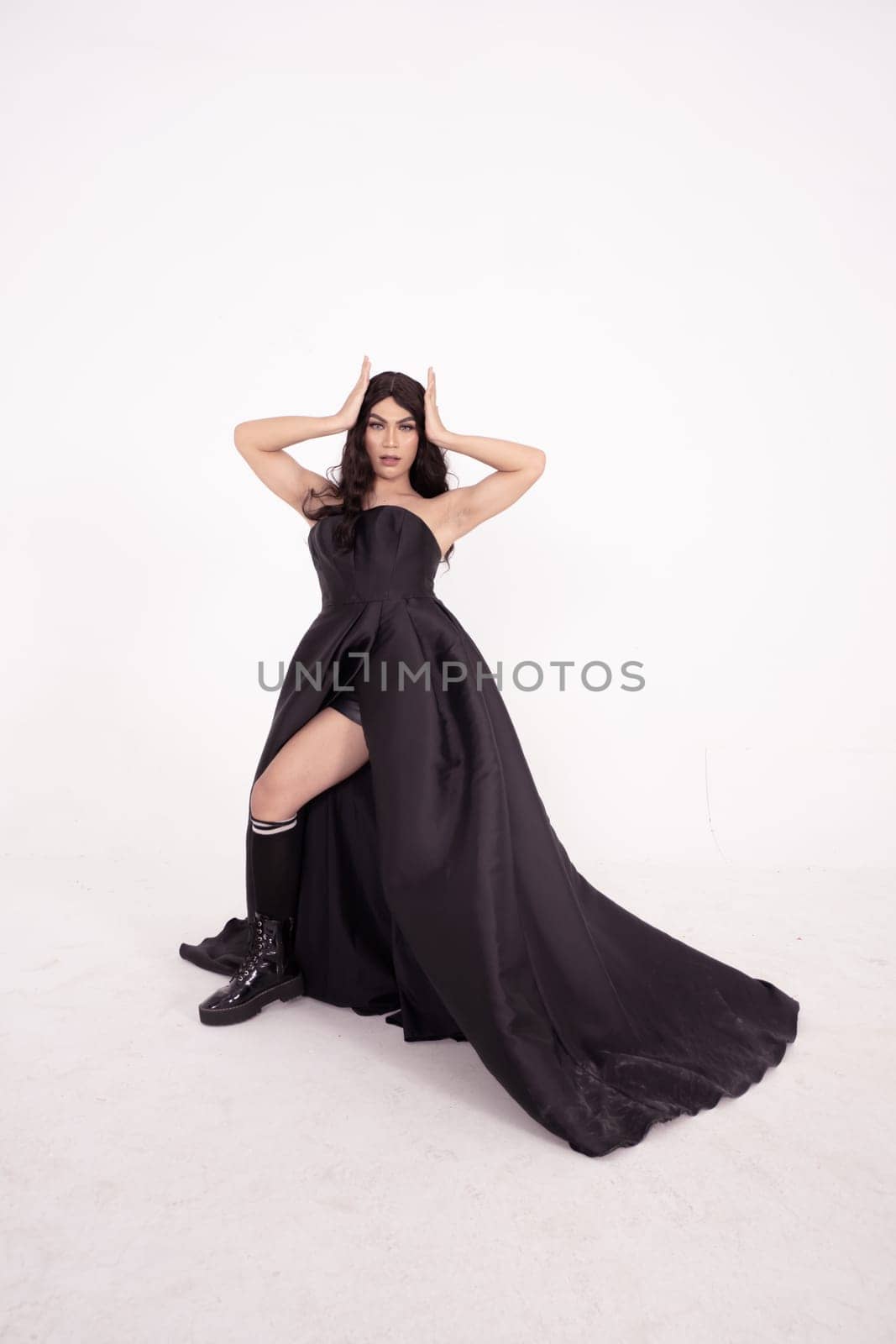 A whole body of an Asian woman in a black dress poses in a white studio with dark brown hair