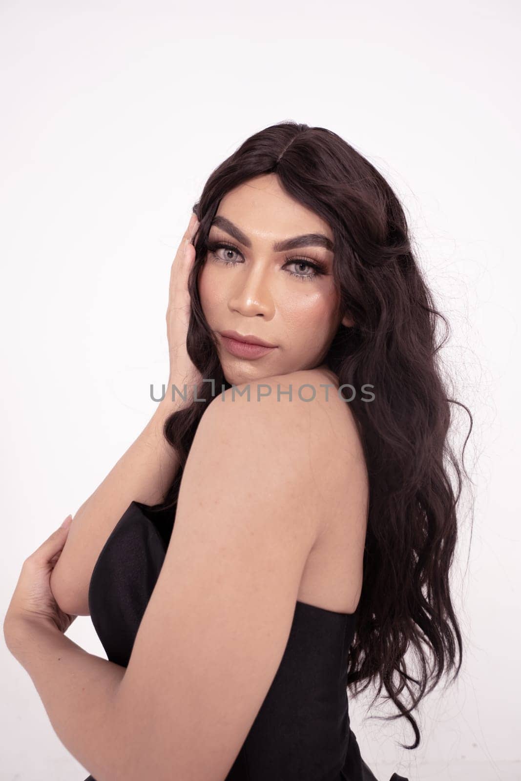 Asian woman sadly holding her face with her hand while wearing a black dress with brown hair