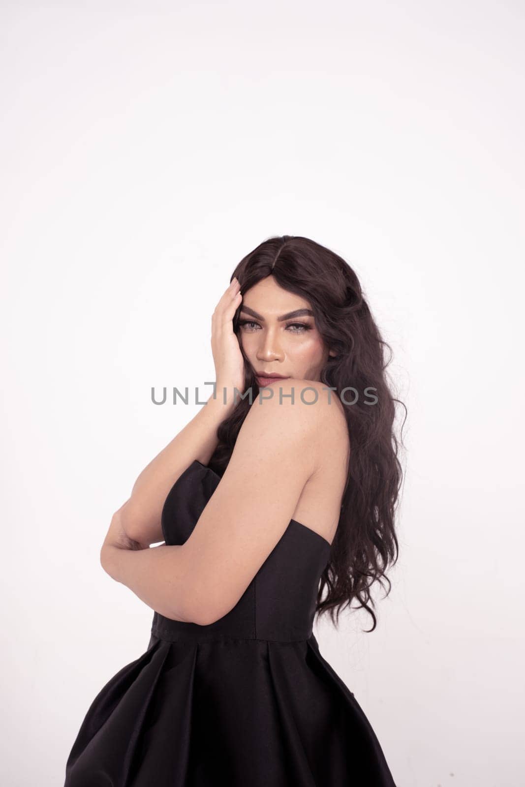 Asian woman sadly holding her face with her hand while wearing a black dress with brown hair
