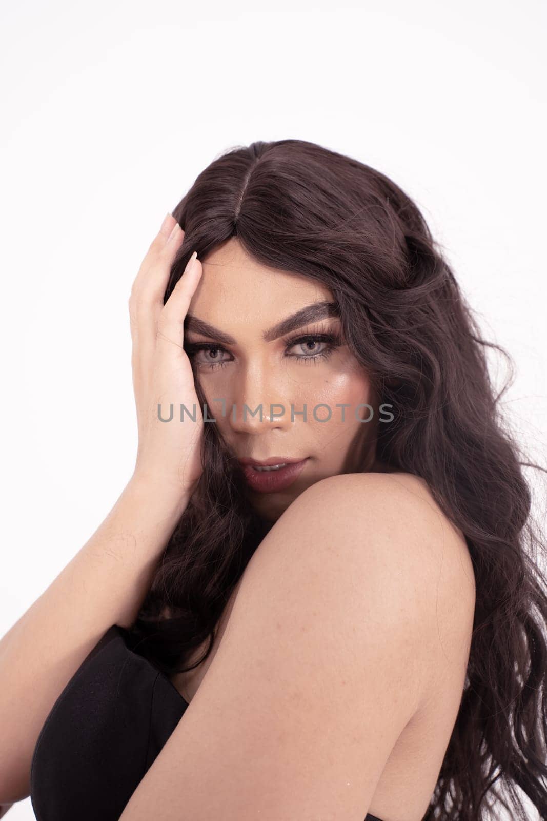 Asian woman sadly holding her face with her hand while wearing a black dress with brown hair