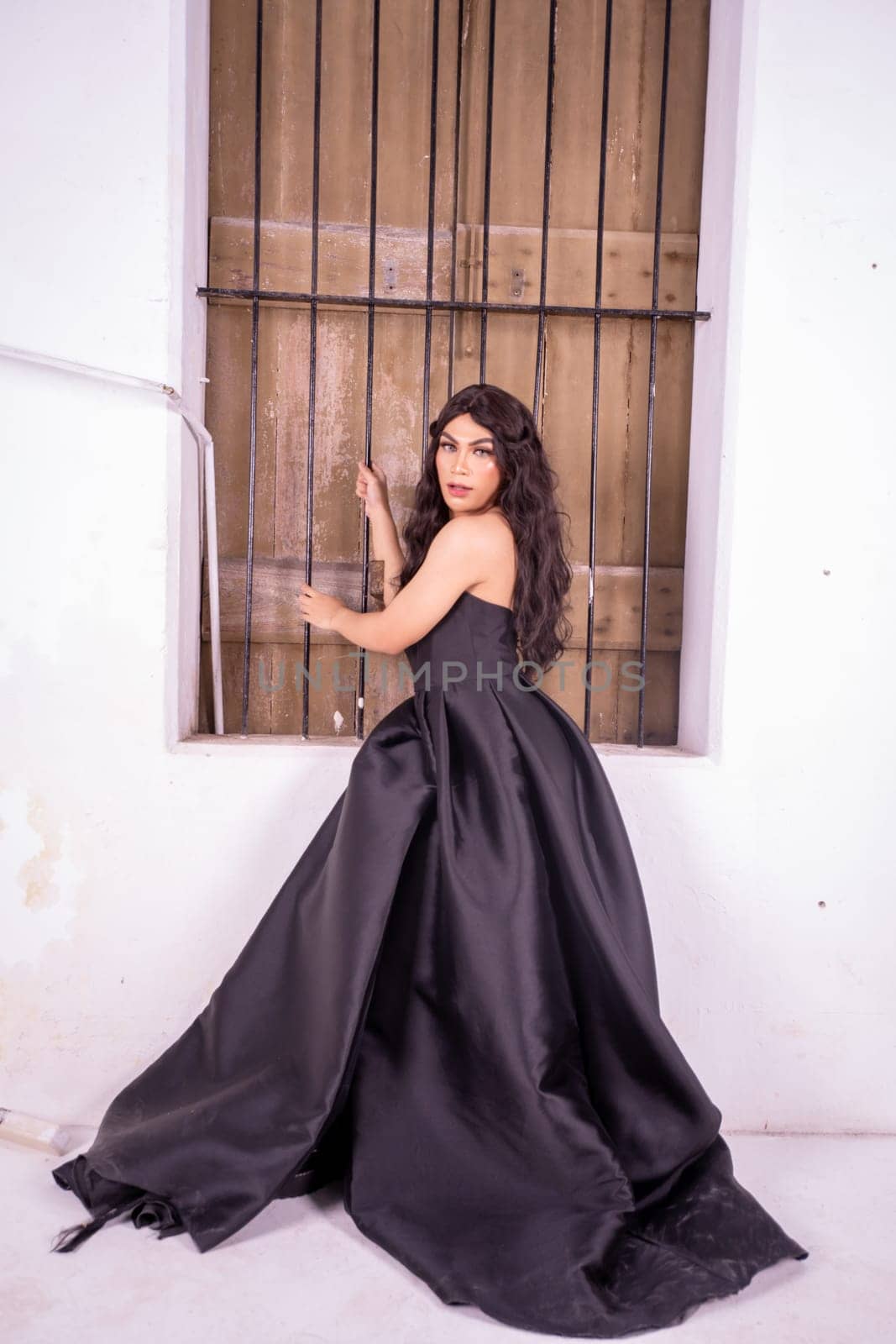 A beautiful Asian woman poses in front of the wooden windows in elegance face inside the white room