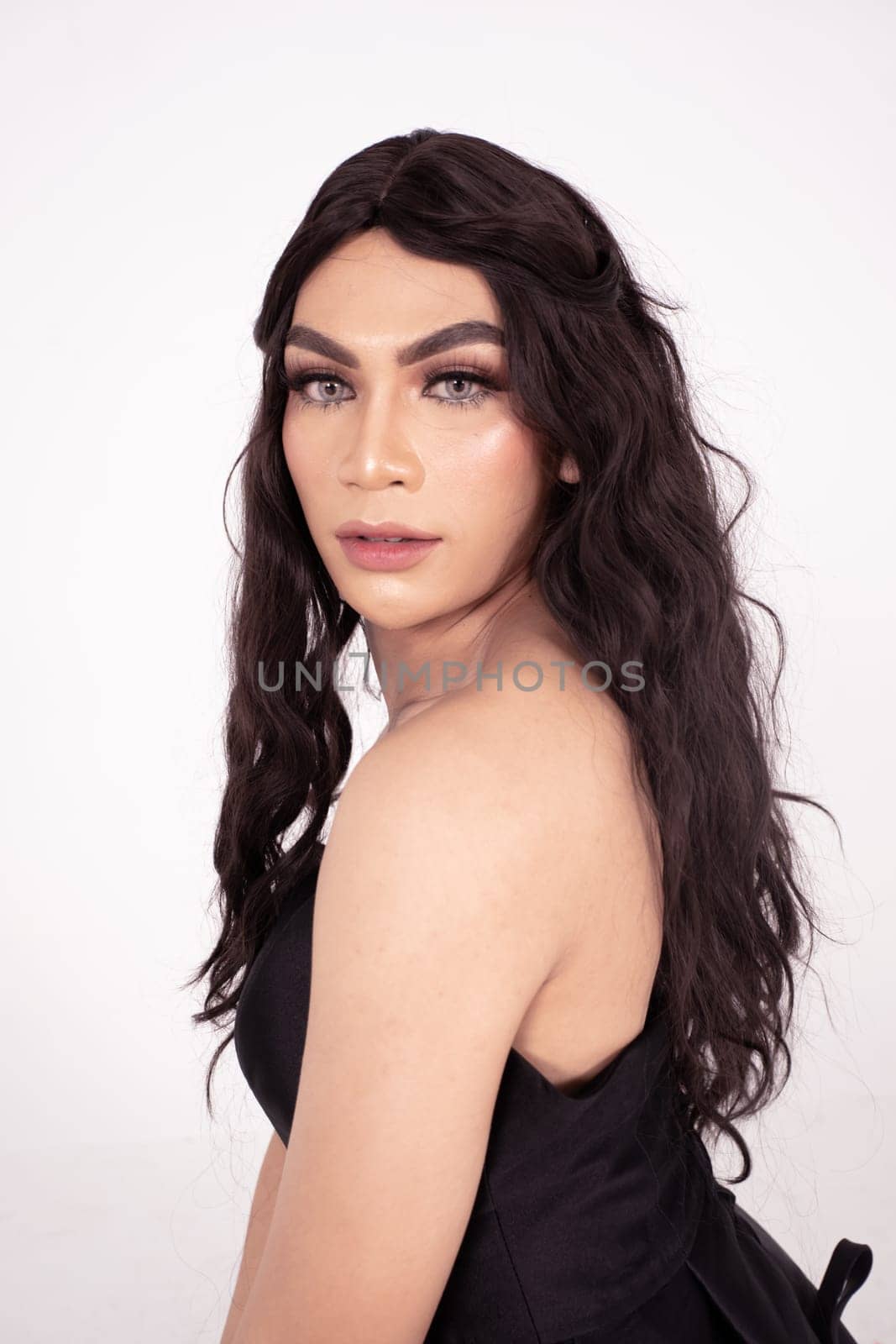 Beautiful Asian woman with dark brown hair posed in a black dress inside the white studio