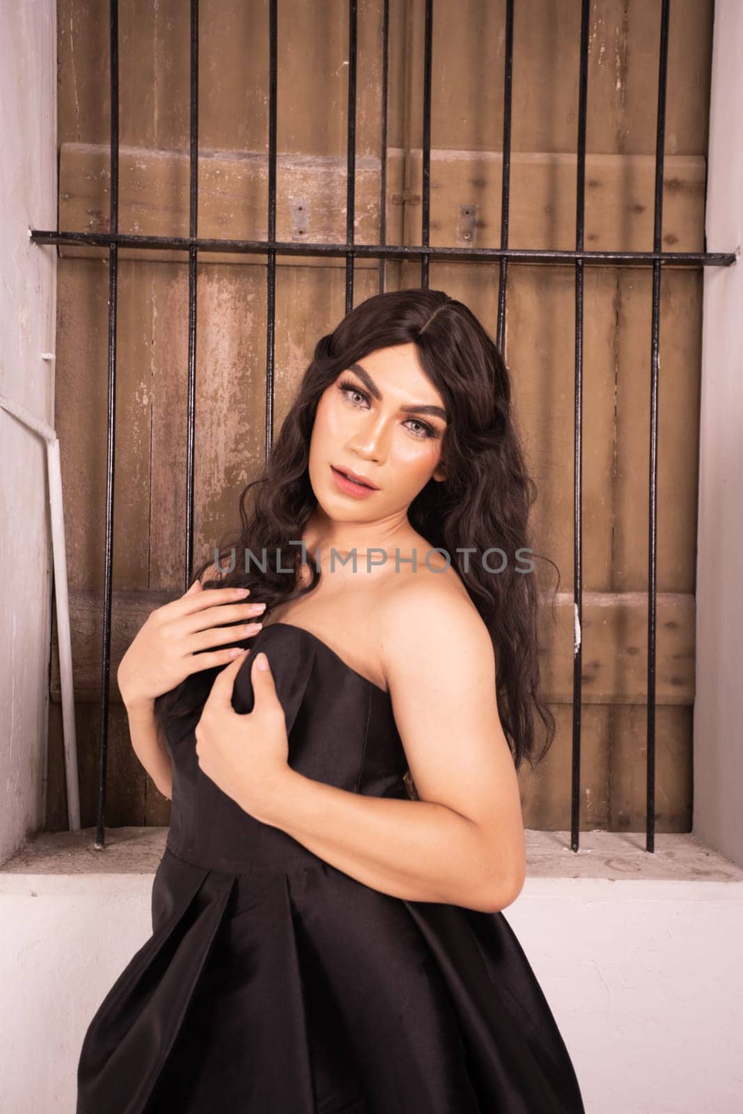 Asian woman poses in front of the old rustic window while wearing a black dress in a white room