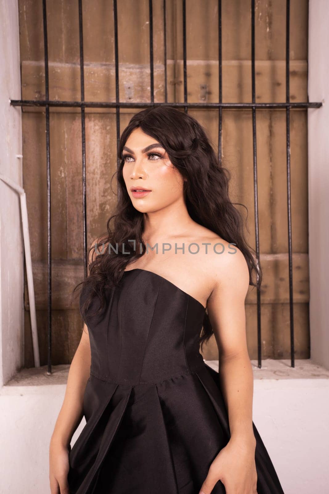 Asian woman poses in front of the old rustic window while wearing a black dress in a white room