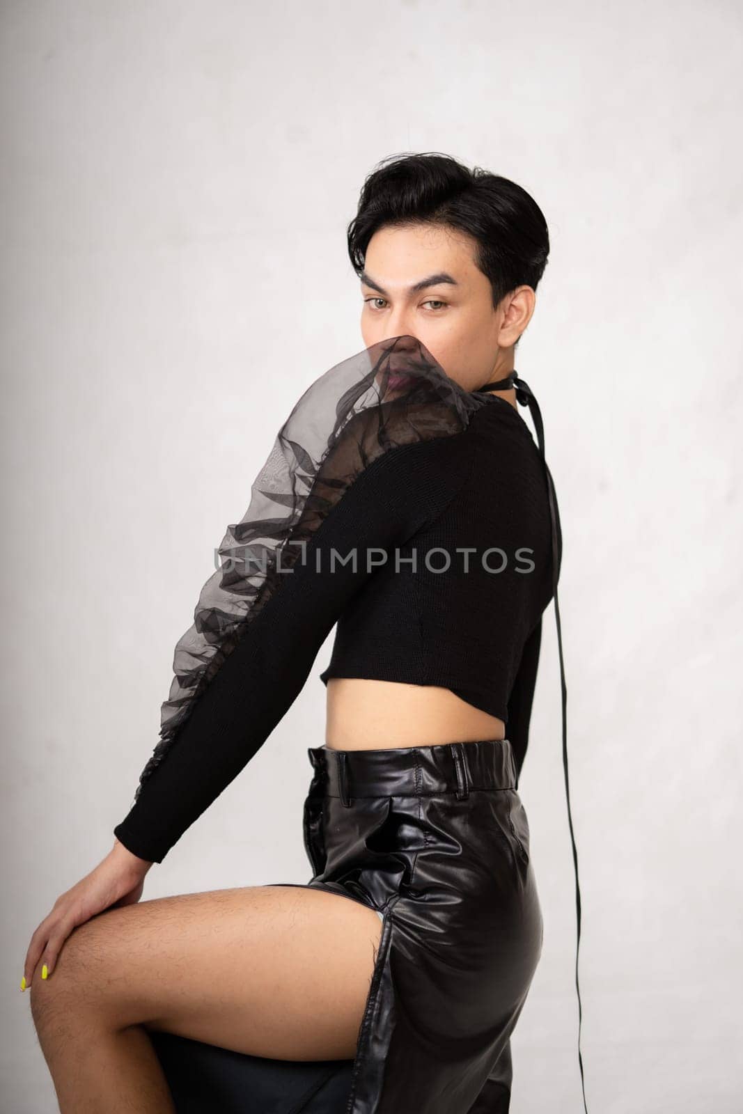 Beautiful Asian man wearing a black tank top with a happy face while in front of the white background