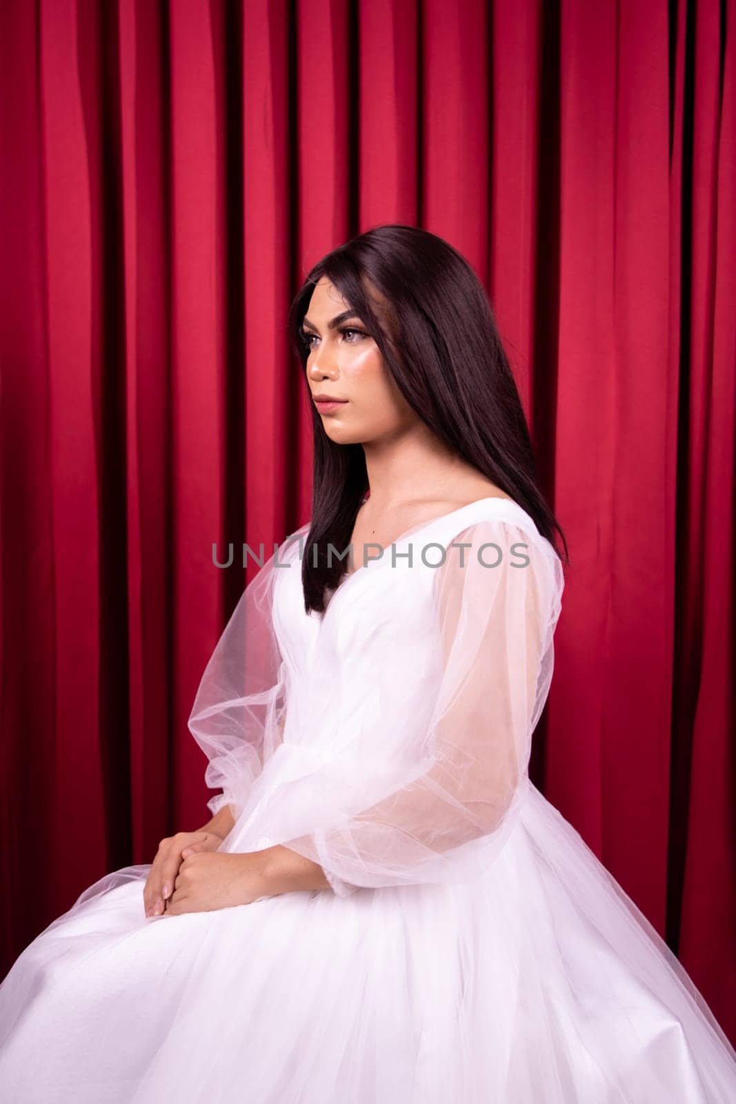 Beautiful Asian woman in white bride dress with black hair in front of the red curtain