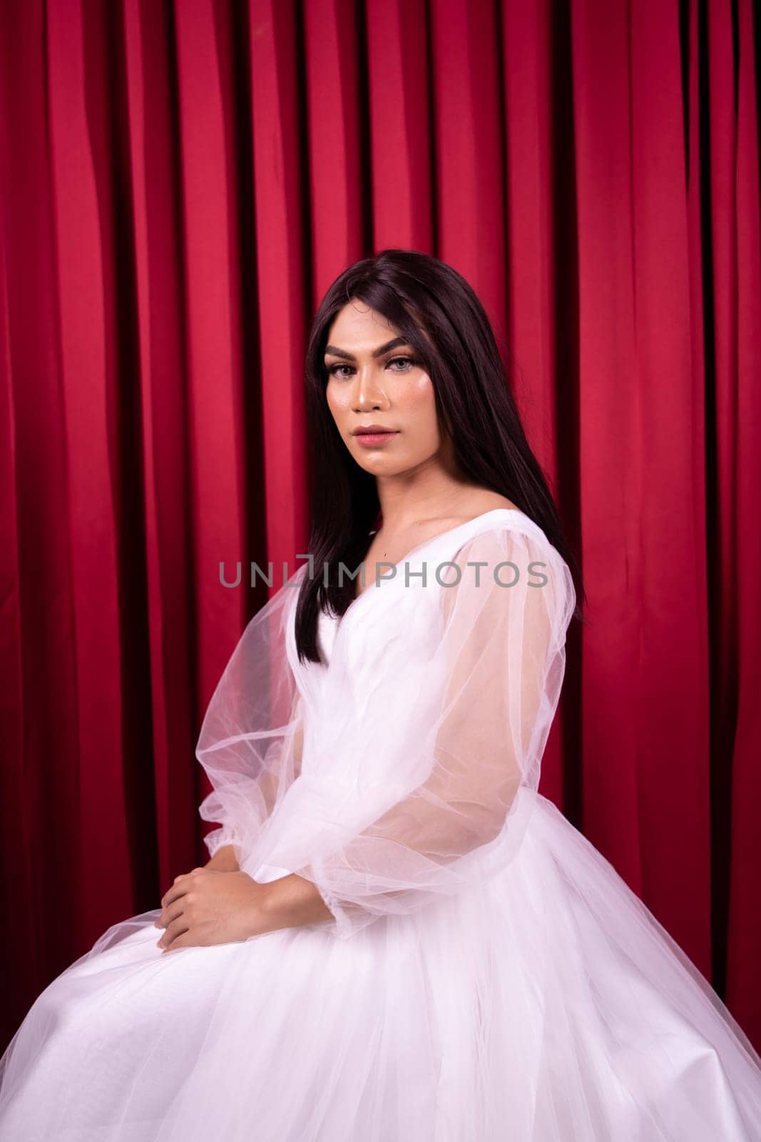 Beautiful Asian woman in white bride dress with black hair in front of the red curtain
