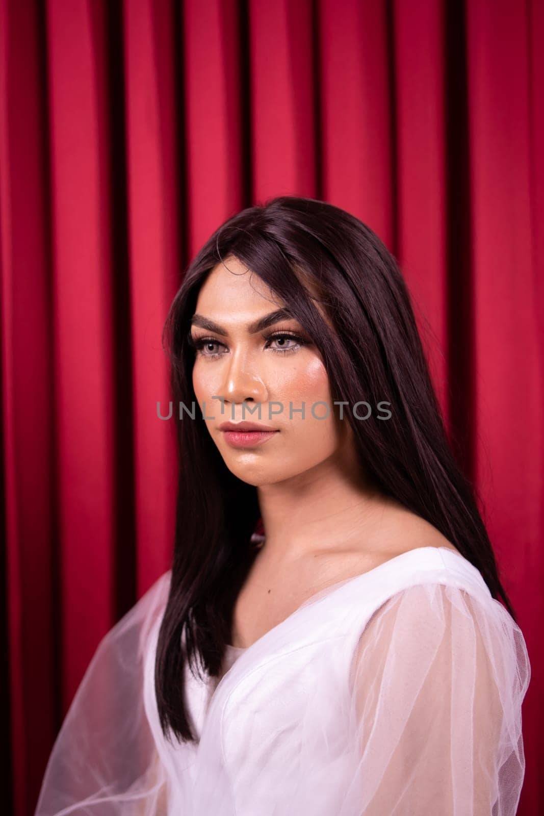 Beautiful Asian woman in white bride dress with black hair in front of the red curtain