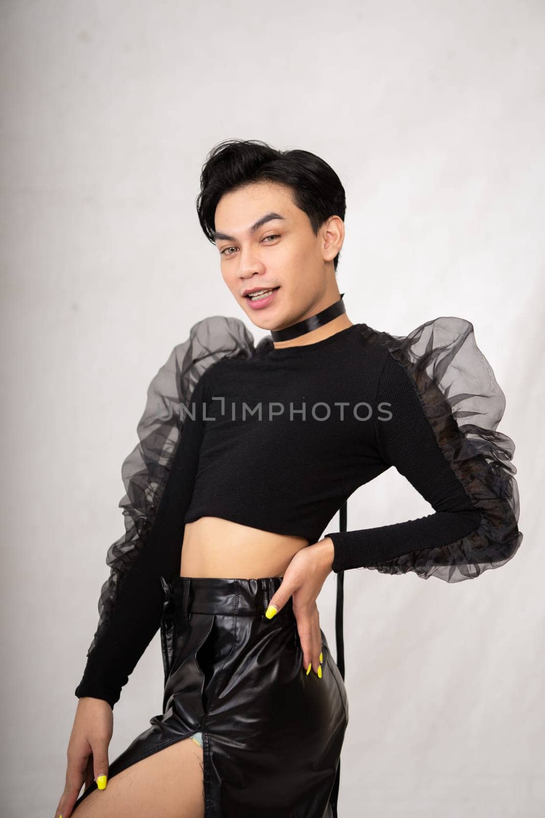 Beautiful Asian man wearing a black tank top with a happy face while in front of the white background