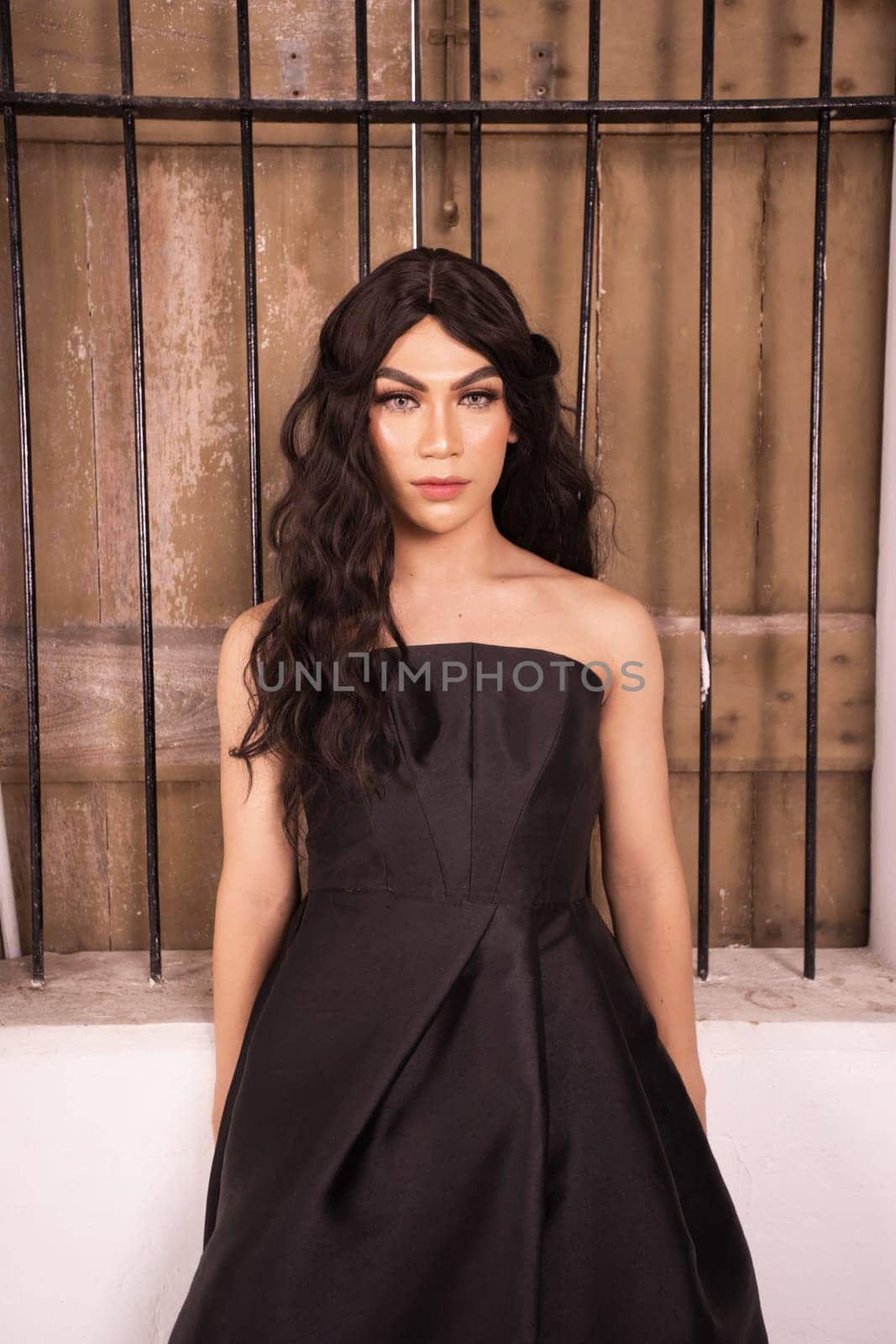 Elegance woman in a black dress standing in front of the rustic wooden window in a white studio