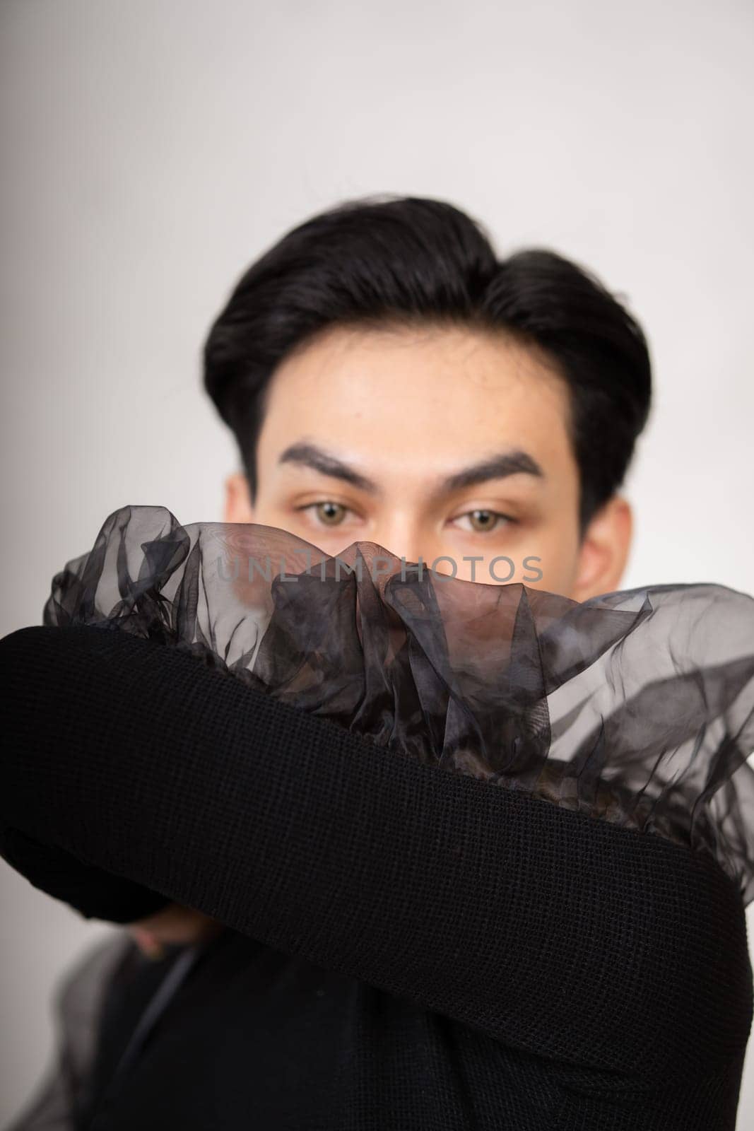 The beautiful man had style in a black costume with black hair and a pretty face inside the white studio