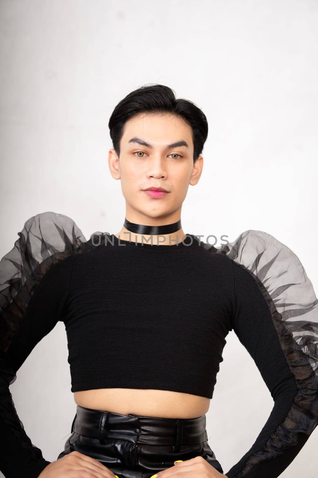 The beautiful man sitting on the chair while wearing a black costume with a pretty face inside the white studio