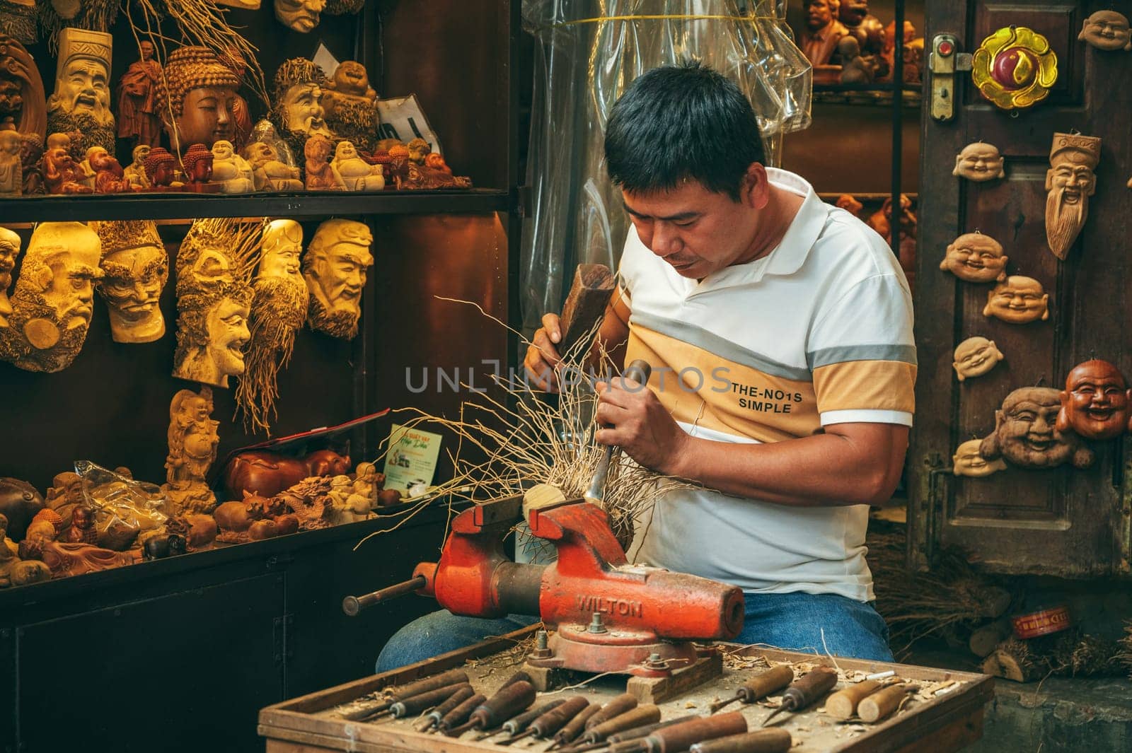 Asian man artisan craftsman carpenter works in wood carving workshop carpentry on street in old town in Hoi An city in Vietnam in Asia. Hoi An, Vietnam - December 1, 2024