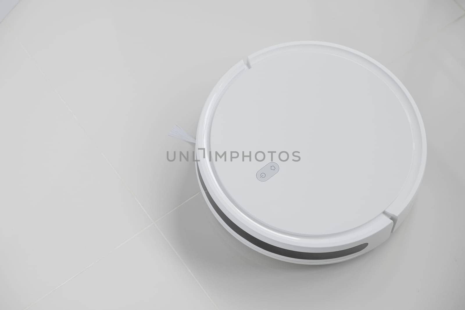 White automatic floor cleaner with side brush on tile flooring, designed for efficient cleaning. Robot vacuum concept of smart home technology for seamless, wireless cleaning of various surfaces