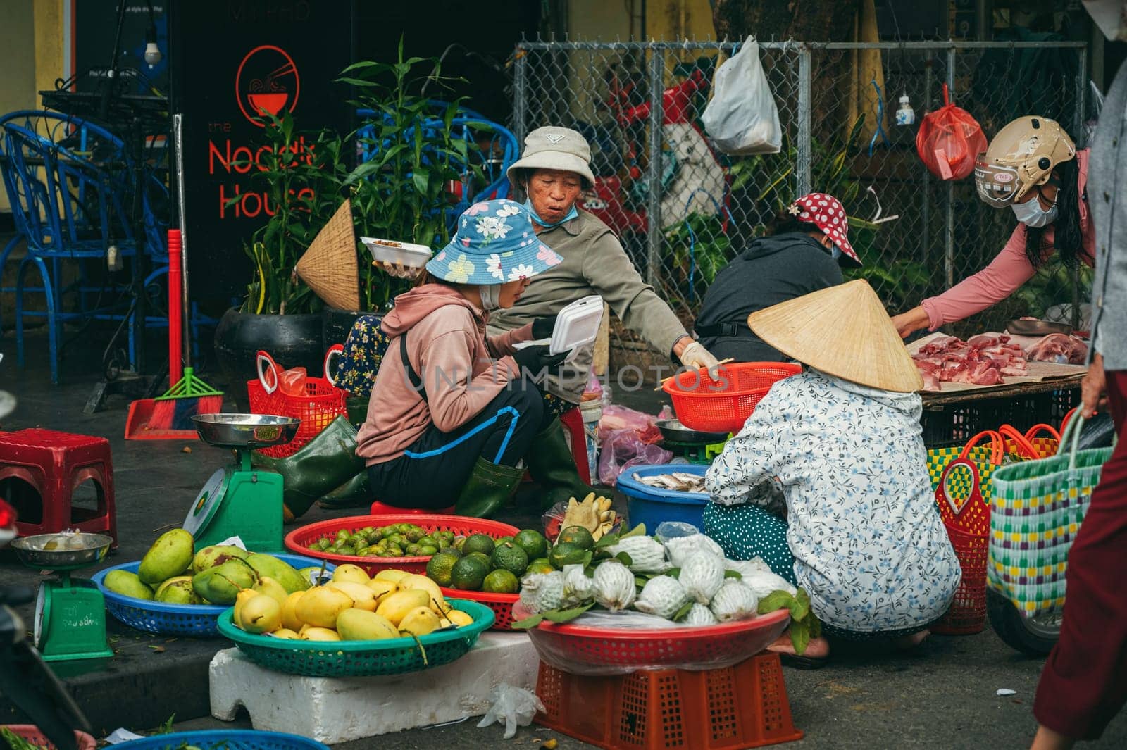 Vietnamese women sellers at Asian street food market in old town in Hoi An in Vietnam in Asia. Hoi An, Vietnam - December 2, 2024