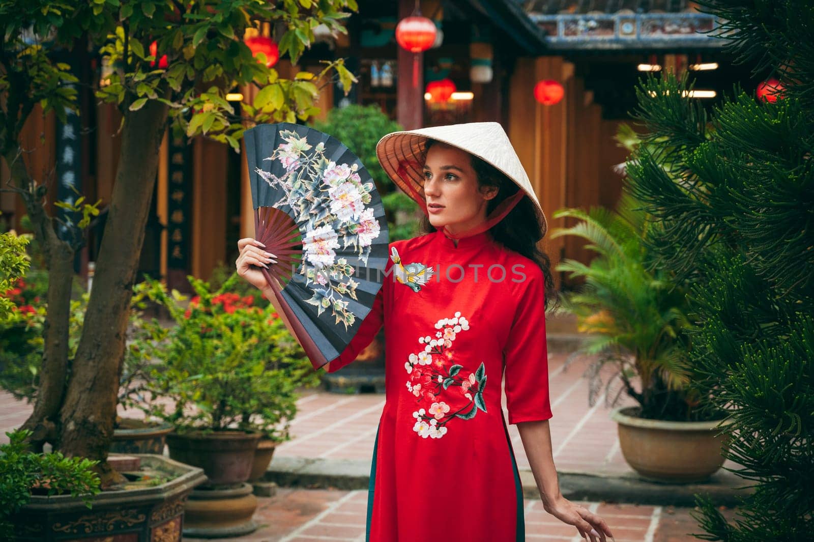 Portrait of a young woman tourist traveler in a Vietnamese cone hat Non La at the Hoi An pagoda in Vietnam in Asia