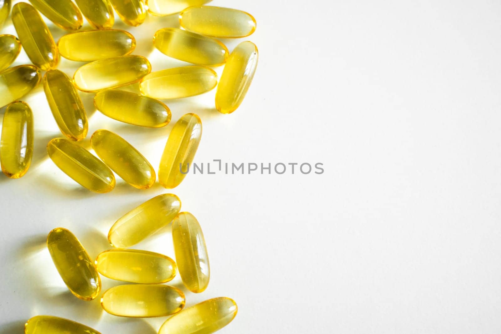 A high-key shot showing shiny yellow omega-3 capsules arranged with ample white space, ideal for health, diet, and wellness themes in editorial or commercial use.