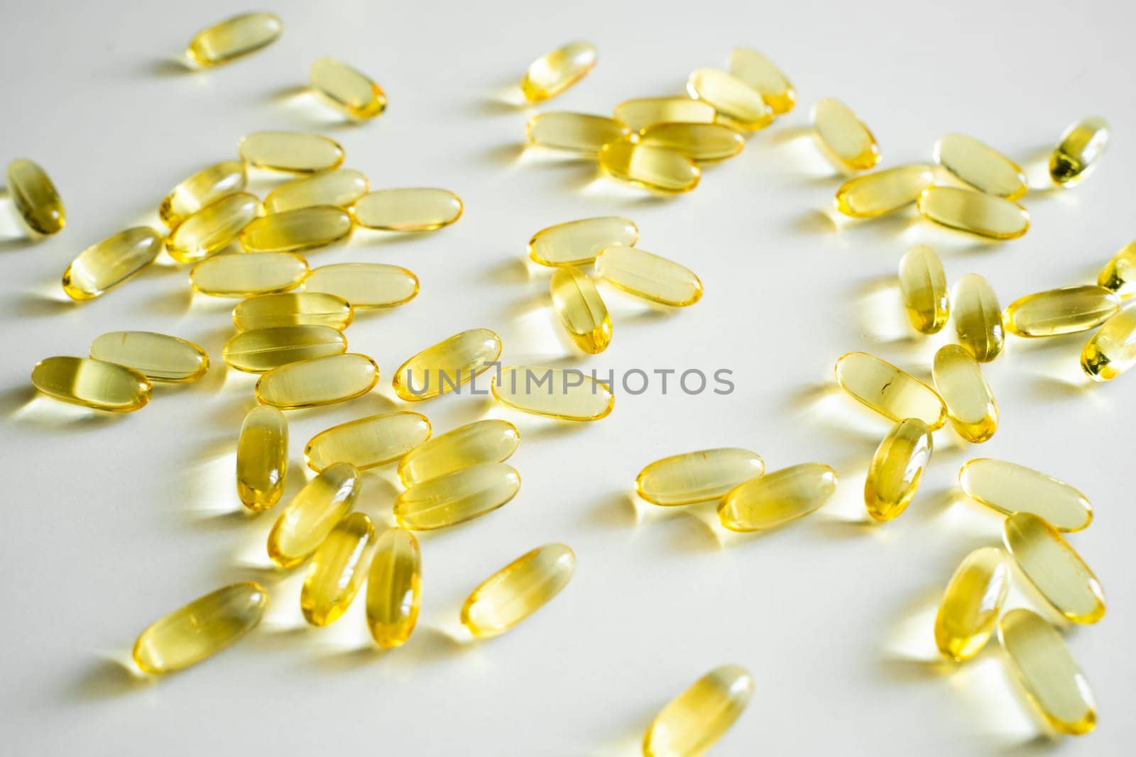 Numerous transparent fish oil gel capsules are randomly scattered on a clean white background, reflecting light and emphasizing clarity and purity in health products.