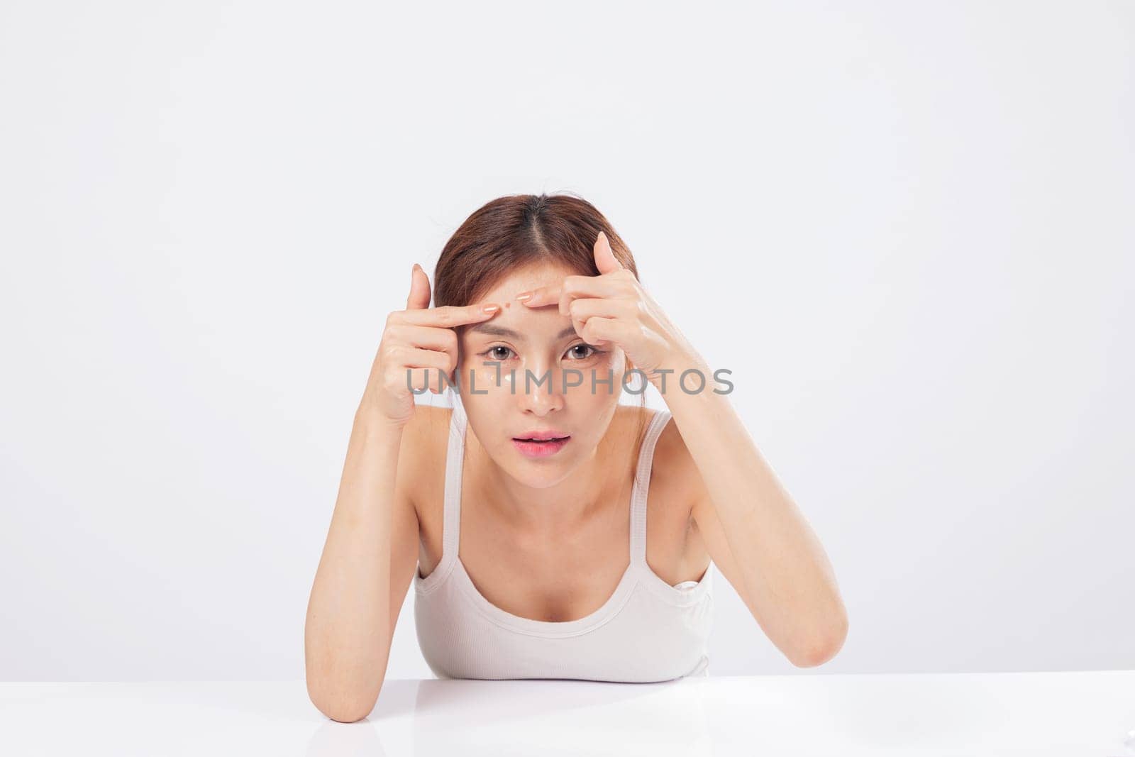 Acne trouble meets careful hands as this teen woman squeezes acne spots, facing blackhead and blemish issues with a clean background and beauty care mindset. isolated studio white background