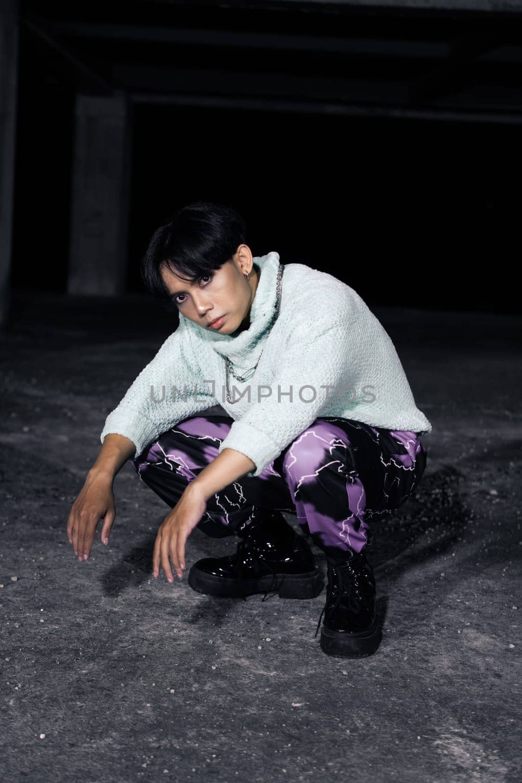 an asian man with black hair squats very masculine in an old building