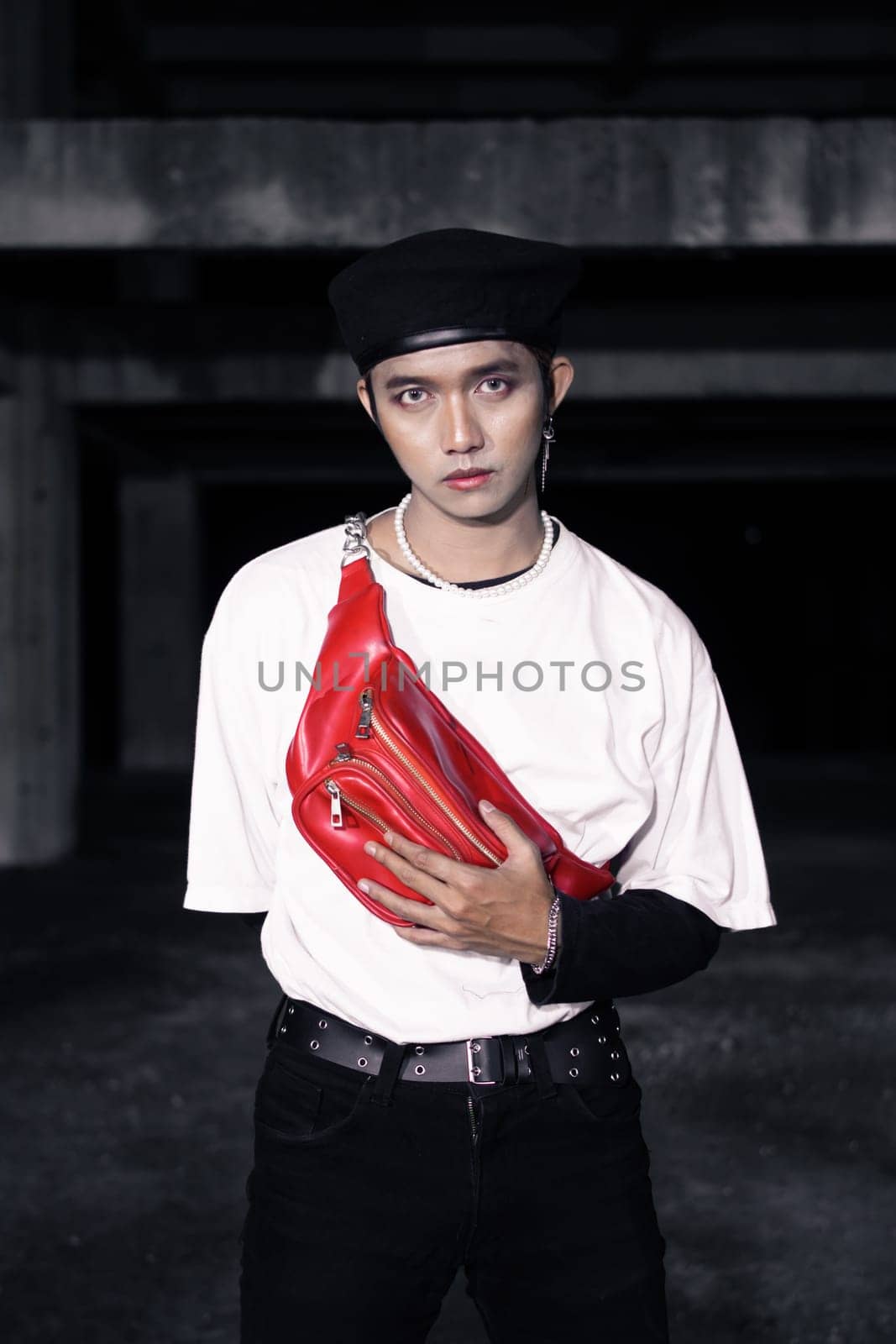 an Asian man standing in an old building with eccentric clothes at night