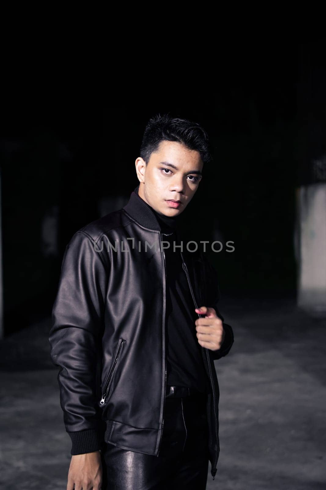 an Asian man wearing a leather jacket and black pants with a handsome face in an old building