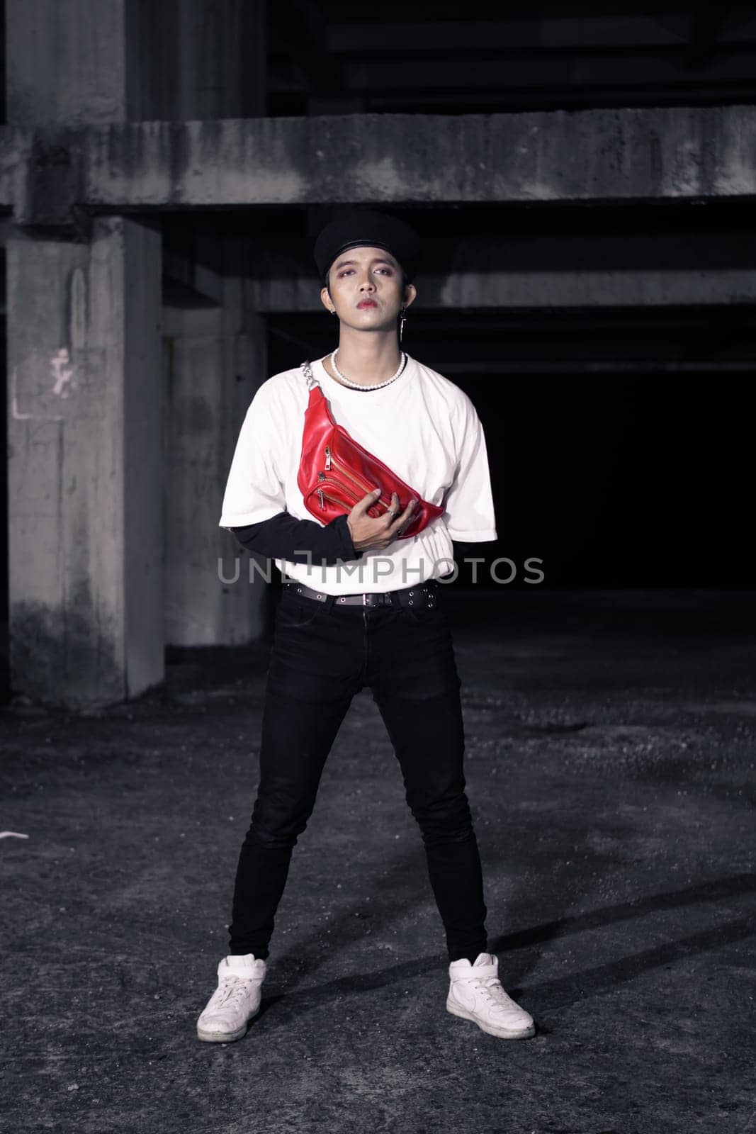 an Asian man standing in an old building with eccentric clothes at night
