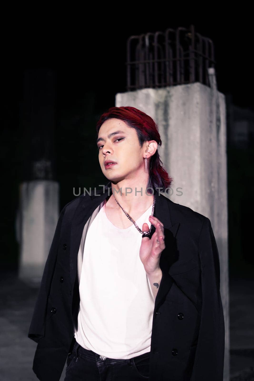 a red haired asian man wearing a white t shirt and black suit in an old building at night