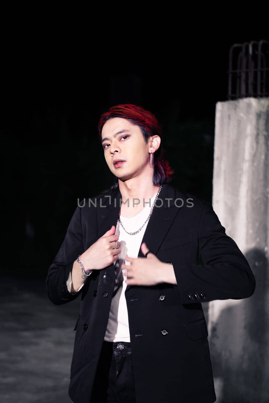 a red haired asian man wearing a white t shirt and black suit in an old building at night
