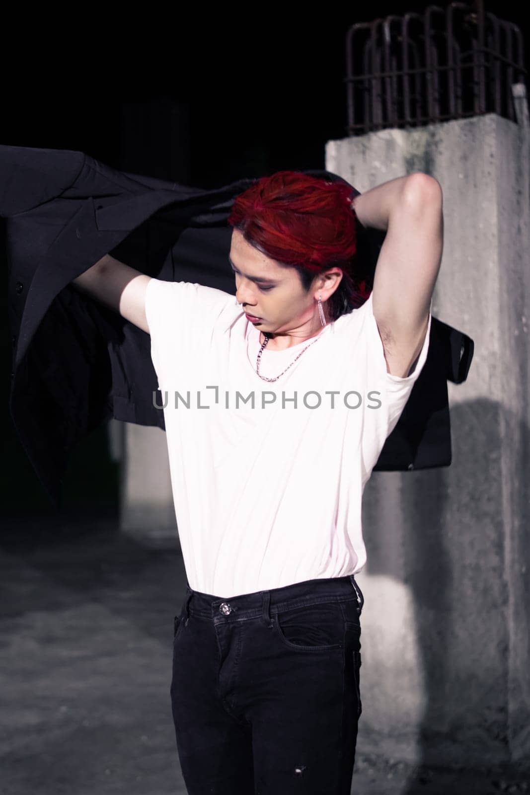 a red haired asian man wearing a white t shirt and black suit in an old building at night