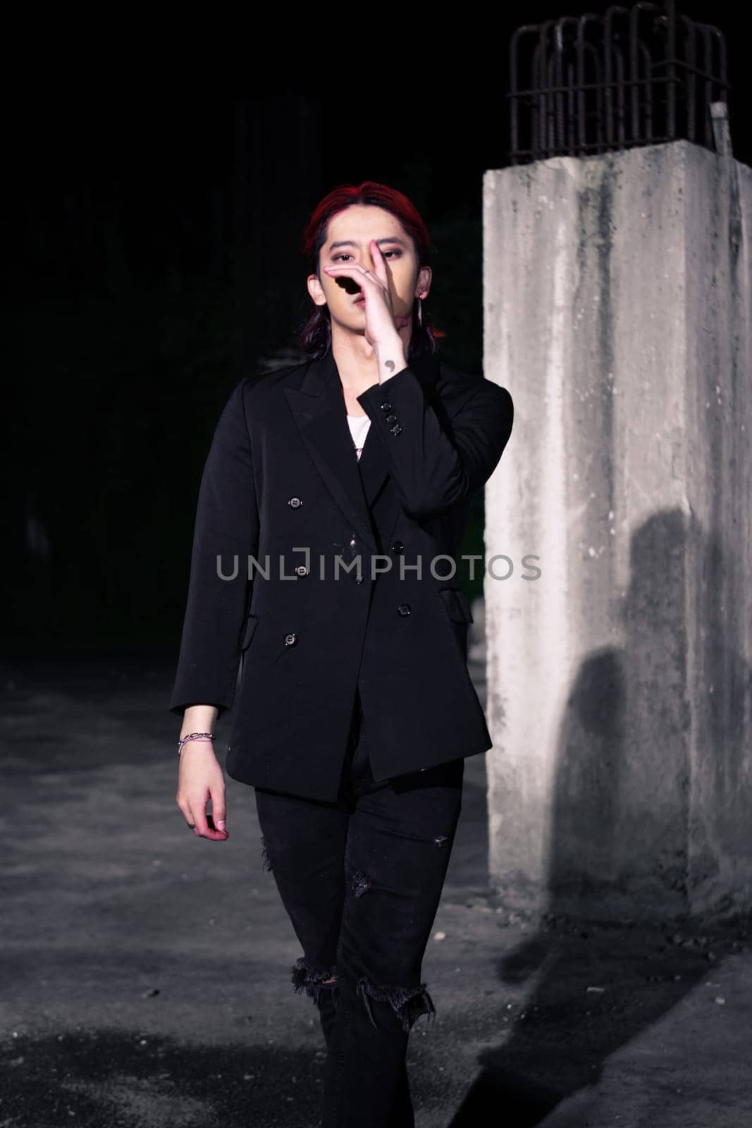 a red haired asian man wearing a white t shirt and black suit in an old building at night